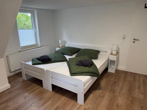 a bedroom with a white bed with green pillows at Ferienhaus am Johannesberg in Heuthen
