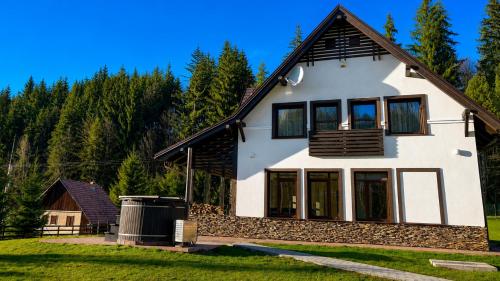 a white house with a black roof at Mountain Paradise & Wellness in Izvoare