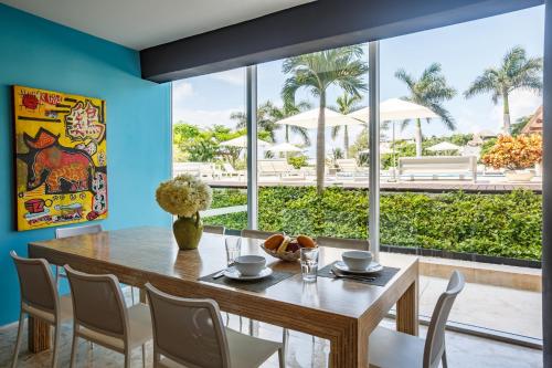 a dining room with a table and chairs and a large window at Magia Beachside Condo in Playa del Carmen