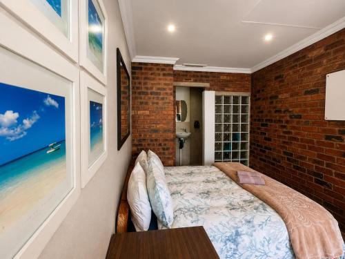 a bedroom with a bed and a brick wall at Limonite Guesthouse in Pretoria