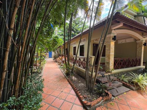 a house with a pathway next to some palm trees at Kep Ocean Inn in Kep