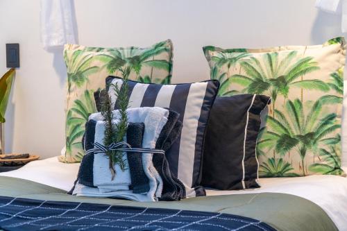 a bed with pillows with palm trees on it at Villa Palmera in Mossel Bay