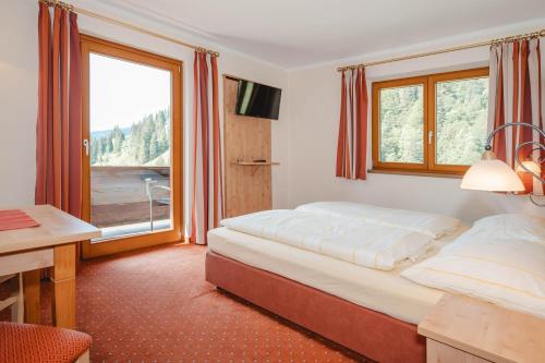 a bedroom with a bed and a desk and a window at Landhaus Rieding in Mühlbach am Hochkönig
