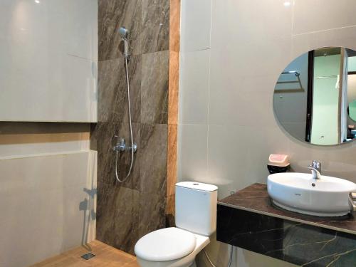 a bathroom with a toilet and a sink and a mirror at Hotel Indria in Bukittinggi