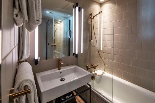 a bathroom with a sink and a mirror and a tub at Scandic Kødbyen in Copenhagen