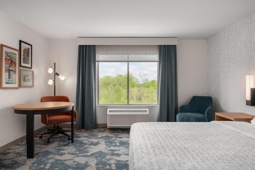 a hotel room with a bed and a desk and a window at Hampton Inn By Hilton Lawrenceburg in Lawrenceburg