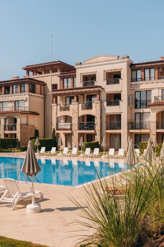 a swimming pool with chairs and umbrellas in front of buildings at Green Life Apartments Sozopol in Sozopol