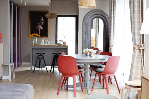 a dining room with a white table and red chairs at Moft Loft. Lovely, comfy apartment. in Cluj-Napoca