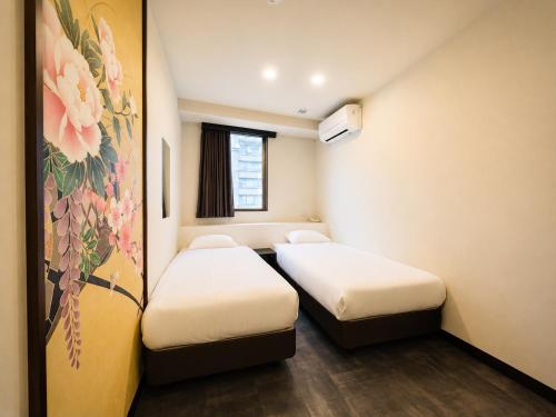 a room with two beds and a painting on the wall at Hotel Arashi Namba No001 in Osaka