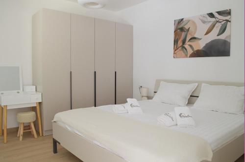 a white bedroom with a large bed with white sheets at Maslina in Crikvenica