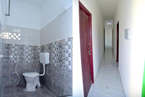 a bathroom with a toilet and a red door at Sai Residency in Pallineriyanur