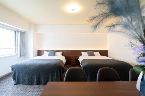 two beds in a room with a table and chairs at Residence Hotel KABUTO Premier in Sapporo