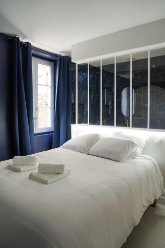 a large white bed in a room with blue curtains at La Nuit Etoilee Balneo Hyper Centre Chalon in Chalon-sur-Saône