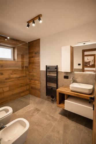 a bathroom with two sinks and two toilets at La Stua de Anny by AMA Val di Fassa in Pozza di Fassa