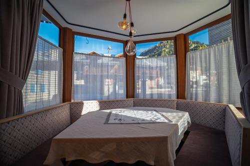 a dining room with a table and large windows at La Stua de Anny by AMA Val di Fassa in Pozza di Fassa