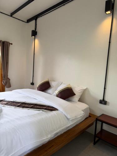 a bedroom with a bed with white sheets and pillows at Mountainblues Hotel in Pai
