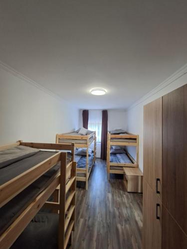 a room with two bunk beds and wooden cabinets at Kitti Panzió in Tiszadada