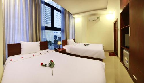 ein Hotelzimmer mit 2 Betten mit Blumen darauf in der Unterkunft Danang Classic Hotel in Đà Nẵng