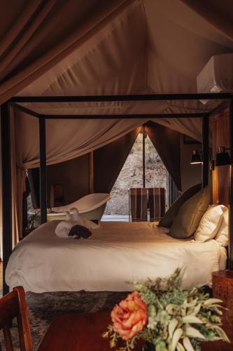 a canopy bed in a tent with flowers on a table at Ontevreden Farm in Montagu
