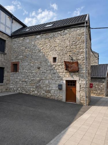 a large stone building with a brown door at La Petite Grange in Aywaille