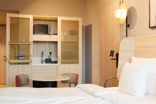 a bedroom with a bed and a table and a microwave at Scandic München Macherei in Munich