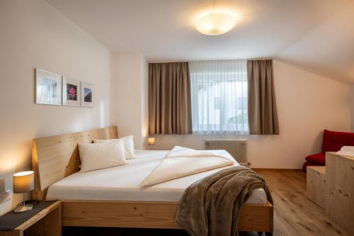 a bedroom with a large bed and a red chair at Ferienwohnungen Tiroler Alpenhof in Innsbruck