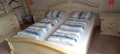 a white bed with blue and white pillows on it at Bungalow Au in Illertissen