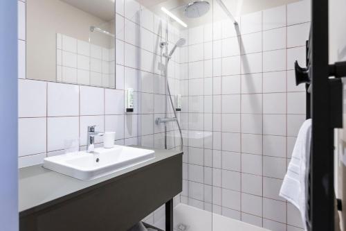 a white bathroom with a sink and a shower at DAFFY Hôtel in Briançon