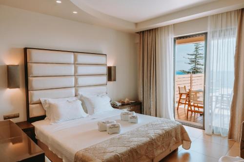 a bedroom with a large bed with a balcony at Sivota Diamond Spa Resort in Syvota