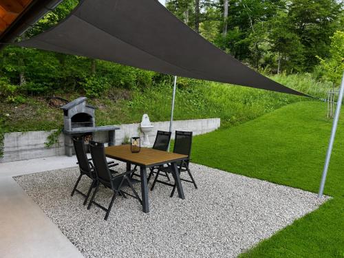 a table and chairs under a black umbrella at Radovna Chalet with Panoramic View in Mojstrana