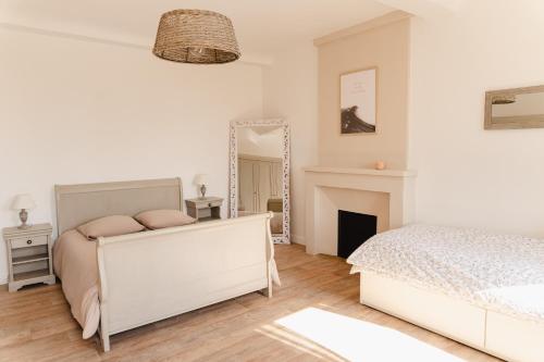 a white bedroom with a bed and a mirror at L'écrin des quatre puits in Cesny-aux-Vignes
