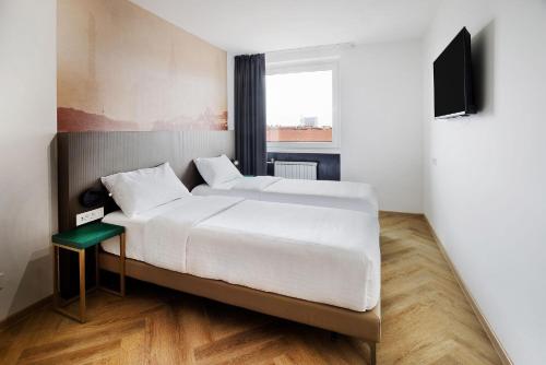 a bedroom with two beds and a flat screen tv at B&B HOTEL Maribor Orel in Maribor