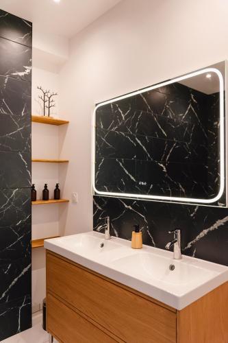 a bathroom with a sink and a large mirror at L'écrin des quatre puits in Cesny-aux-Vignes