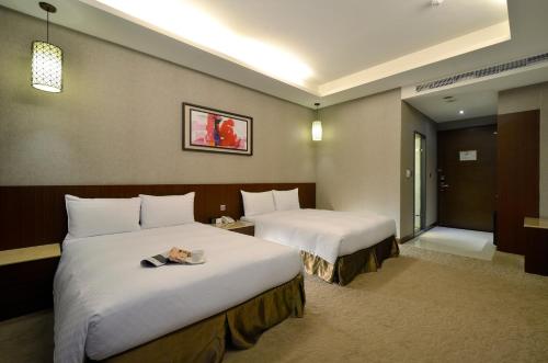 a hotel room with two beds and a window at Guanko Hotel in Chiayi City