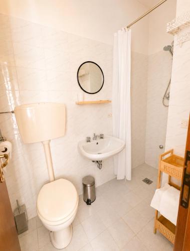 a white bathroom with a toilet and a sink at La Scaletta in San Colombano