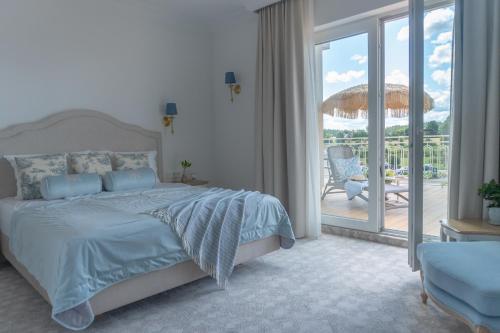 a bedroom with a bed and a balcony with an umbrella at Hotel Kiston in Sulęczyno