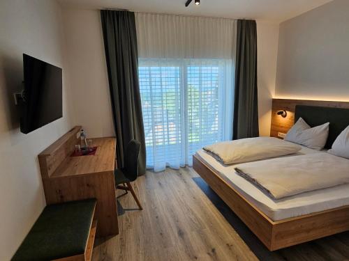 a bedroom with a bed and a desk and a television at Packerhöhe in Pack