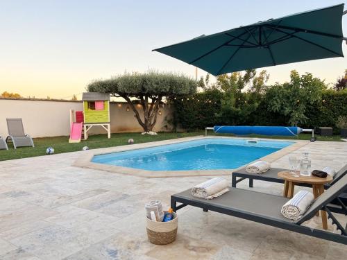 a swimming pool with a table and an umbrella at Studio neuf avec acces piscine in Valergues