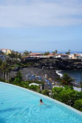 a person in a swimming pool next to a beach at Landmar Playa La Arena in Puerto de Santiago