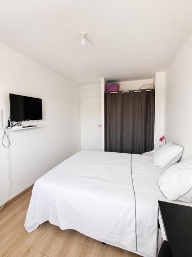 a bedroom with a white bed and a flat screen tv at Beautiful, modern room in Saint-Paul-de-Varax