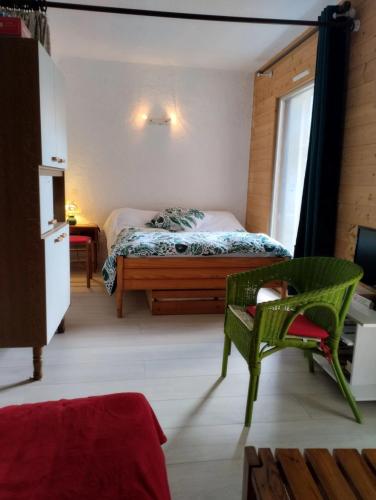 a bedroom with a bed and a green chair at Studio confortable à Cauterets - 40 m² - Vue sur la montagne in Cauterets