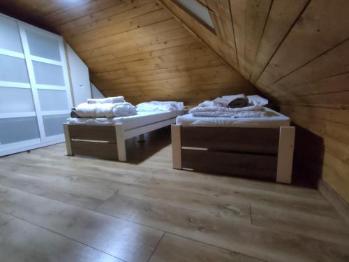 two beds in a room with a wooden ceiling at LŰN Apartman in Dunaföldvár