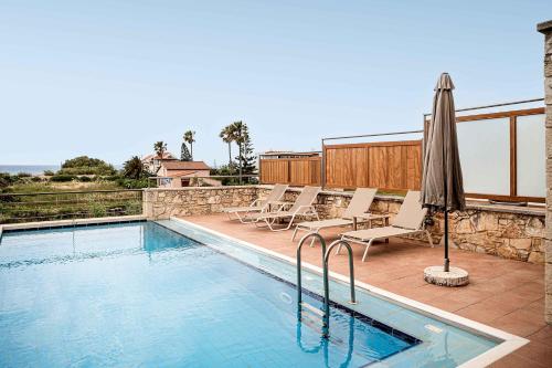 a swimming pool with chairs and an umbrella at Corali Villas - Seaview, Private Pools, 450 to Beach in Kolymvari