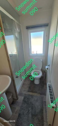 a bathroom with a shower and a toilet and a window at Caravan 133 snowdon summit 090 in Barmouth