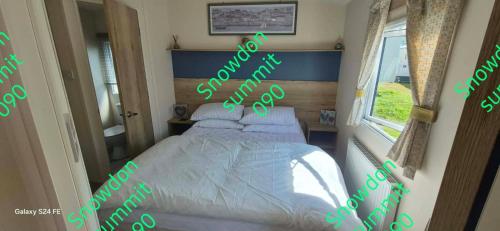 a bedroom with a bed and a window with green words at Caravan 133 snowdon summit 090 in Barmouth