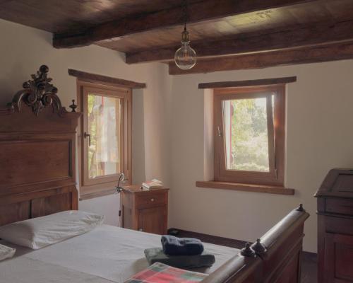 a bedroom with a bed and two windows at Casetta dalle finestre rosse in Bedonia
