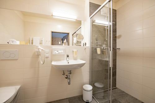 a bathroom with a sink and a shower at JUFA Hotel Maria Lankowitz am See in Maria Lankowitz