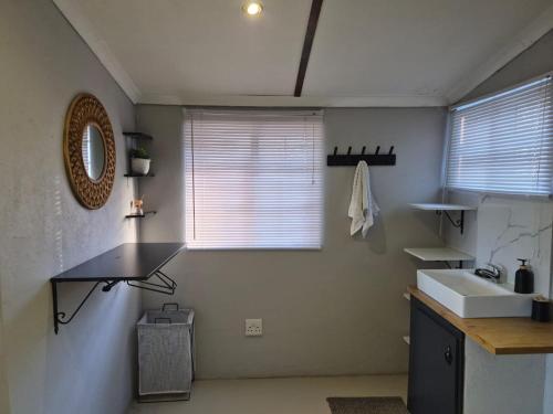 a bathroom with a sink and a mirror and a window at Toekoms Inn in Aliwal North