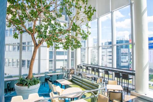 a room with a tree and tables and chairs at Shibuya Excel Hotel Tokyu in Tokyo