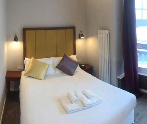a bedroom with a white bed with two towels on it at Friars Wynd Guest Rooms in Stirling